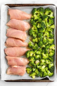 Chicken tenderloins separated from vegetables on a sheet pan to ensure even cooking.